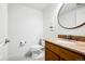Powder room with wood vanity with granite countertop, toilet, and round mirror at 5582 Twilight Way, Parker, CO 80134