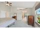 Spacious bedroom with a ceiling fan, wood dressers, and view to another room and backyard at 7226 S Eagles Nest Cir, Littleton, CO 80127