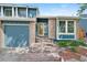 Close up of the brick front entrance with blue siding and two car garage on a sunny day at 7226 S Eagles Nest Cir, Littleton, CO 80127