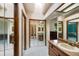 Hallway with mirrored closets leading to a bathroom with wood vanity and large mirror at 7226 S Eagles Nest Cir, Littleton, CO 80127