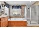 Bright bathroom featuring a soaking tub, large window, and glass shower enclosure at 5778 S Duquesne Ct, Aurora, CO 80016