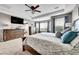 Bedroom with a TV, bay window, dresser, en suite bathroom, and large king bed at 5778 S Duquesne Ct, Aurora, CO 80016