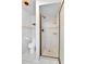 Bathroom featuring a tiled shower with glass door, modern toilet, and neutral tile at 7796 S Marshall Ct, Littleton, CO 80128