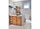 Bathroom with wooden cabinets, granite countertop, vessel sink, large mirror, and tiled floors at 7796 S Marshall Ct, Littleton, CO 80128