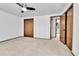 Bright bedroom featuring neutral carpet, ceiling fan, and wood doors leading to hallway and closet at 7796 S Marshall Ct, Littleton, CO 80128