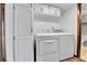 Bright laundry room with washer, dryer, storage cabinet, and access to a half bath at 7796 S Marshall Ct, Littleton, CO 80128
