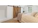 Charming bedroom featuring wood floors, large sliding barn doors, and a comfortable bed at 4508 W 34Th Ave, Denver, CO 80212