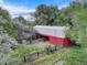 Rustic red barn with a gray roof surrounded by lush greenery and fencing at 14650 Tejon St, Broomfield, CO 80023