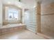 Bathroom featuring a soaking tub, glass block shower, large window, and neutral tile at 4800 E Cedar Ave, Denver, CO 80246