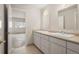 Bathroom featuring double sinks, white vanity and an open door to an adjacent unfinished room at 4800 E Cedar Ave, Denver, CO 80246