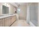 Bright bathroom features a shower, bath and sink with tile floors and a white vanity at 4800 E Cedar Ave, Denver, CO 80246