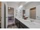 Well-lit bathroom with dual sinks, large mirror, and decorative tile flooring, with views to the office and shower area at 11926 Olive St, Thornton, CO 80233