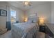 Cozy bedroom with a ceiling fan, patterned bedding, a window with curtains, and a nightstand at 11926 Olive St, Thornton, CO 80233