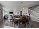 Elegant dining room with a modern chandelier, a wooden dining table, and a view of the living room and stairs at 11926 Olive St, Thornton, CO 80233