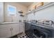 Bright laundry room featuring grey cabinets and stainless steel washer and dryer at 11926 Olive St, Thornton, CO 80233