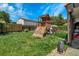 Backyard features a wooden playset on green grass with surrounding trees and a view of the house at 7101 Alan Dr, Denver, CO 80221
