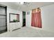 Bedroom features a dresser with a decorative mirror and a window with red curtains at 7101 Alan Dr, Denver, CO 80221