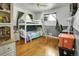 A cozy bedroom with a white bunk bed frame, wood floors, and neutral curtains at 7101 Alan Dr, Denver, CO 80221