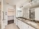 Bathroom with double sink vanity, granite countertops, and a glass door shower at 15217 Xenia St, Thornton, CO 80602