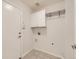 Bright laundry room with tile flooring, white cabinets, and hanging rack at 15217 Xenia St, Thornton, CO 80602