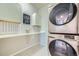 Laundry room with stacked washer and dryer, stylish cabinets, and geometric wallpaper at 9880 E 160Th Pl, Brighton, CO 80602