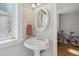 Bright bathroom featuring pedestal sink, oval mirror, and natural light from the window at 1580 N Franklin St, Denver, CO 80218