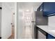 Hallway leading to bathroom with stainless steel refrigerator and blue cabinetry at 70 N Grant St # 10, Denver, CO 80203