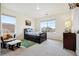 Bright bedroom featuring a large window with neighborhood views, a rocking chair and a cozy rug at 14696 Bonsmara Dr, Mead, CO 80542