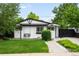 Charming white and black home featuring a swing, black framed windows, and a well-manicured lawn at 1264 Uinta St, Denver, CO 80220
