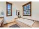 Bright bathroom featuring a soaking tub, tile surround, and natural lighting from two windows at 19 Red Fox Ln, Littleton, CO 80127