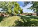 Spacious backyard with lush green grass, mature trees, storage shed, slide, and hammock at 8063 S Otis Ct, Littleton, CO 80128