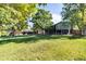Large backyard with mature trees providing shade, lush green grass, and an inviting back deck with stairs at 8063 S Otis Ct, Littleton, CO 80128
