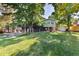 Spacious backyard featuring a trampoline, lush green grass, large trees, and a back deck; perfect for recreation at 8063 S Otis Ct, Littleton, CO 80128