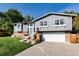 Charming two-story home with gray siding, brick accents, a two-car garage and well-manicured lawn at 8063 S Otis Ct, Littleton, CO 80128