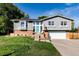 Charming home featuring a manicured lawn, brick accents, and a striking turquoise front door at 8063 S Otis Ct, Littleton, CO 80128