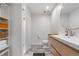 Modern bathroom with white tiled shower, sleek vanity, and stylish wood-look flooring at 8691 S Sicily Ct, Aurora, CO 80016