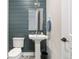 Stylish powder room with blue shiplap accent wall, pedestal sink, and decorative tile flooring at 8691 S Sicily Ct, Aurora, CO 80016