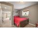 Carpeted bedroom featuring a wood-framed bed with red bedding, a window, and an open doorway leading to another room at 9200 W Indore Dr, Littleton, CO 80128