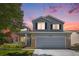 Charming two-story home featuring a covered porch, manicured lawn, and brick accents at dusk at 9200 W Indore Dr, Littleton, CO 80128