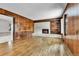 Spacious living room featuring hardwood floors, wood paneling, and a brick fireplace with built-in shelves at 7058 S Madison Way, Centennial, CO 80122
