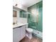 Bathroom featuring a green-tiled shower with glass doors, white vanity, and gold accents at 5450 Mohawk Rd, Littleton, CO 80123