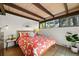 Comfortable bedroom featuring exposed beams, a red floral bedspread, and a neutral color scheme at 5450 Mohawk Rd, Littleton, CO 80123