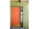Close up of vibrant orange front door with vintage hardware and sidelight window at 5450 Mohawk Rd, Littleton, CO 80123