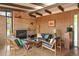 Spacious living room with a brick fireplace, wood paneling, and retro modern furniture at 5450 Mohawk Rd, Littleton, CO 80123