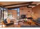 Inviting living room with brick fireplace, wood paneled walls, and beam ceiling at 5450 Mohawk Rd, Littleton, CO 80123