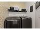 Laundry room with shelving, stylish wallpaper, and modern washer/dryer set at 17036 Park Trail Dr, Monument, CO 80132