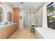 Bright bathroom with natural wood cabinets, double vanity, soaking tub and a glass enclosed shower at 332 S Franklin St, Denver, CO 80209