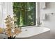 Luxurious soaking tub with a sleek faucet, paired with a black framed window and a lush green view at 332 S Franklin St, Denver, CO 80209