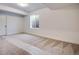 Unfinished basement features neutral carpet, a window, and a white door at 17822 E 107Th Pl, Commerce City, CO 80022