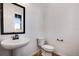 Contemporary powder room featuring a pedestal sink, toilet, mirror, and window at 17822 E 107Th Pl, Commerce City, CO 80022